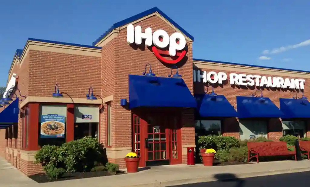 Exterior of an IHOP restaurant featuring red brick walls, blue awnings, and a prominently displayed logo.