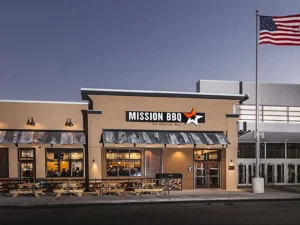 Mission BBQ restaurant exterior with American flag at dusk