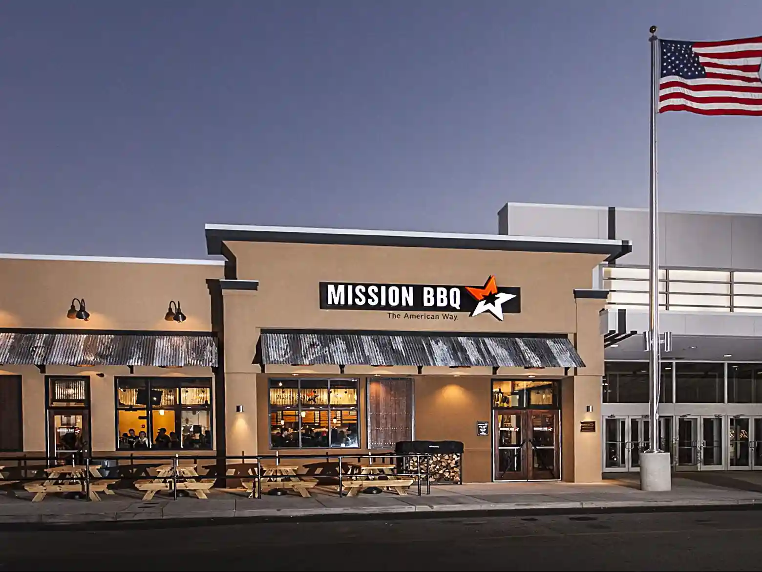 Mission BBQ restaurant exterior with American flag at dusk