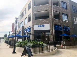 Exterior view of Blue Sushi Sake Grill with outdoor seating and blue umbrellas