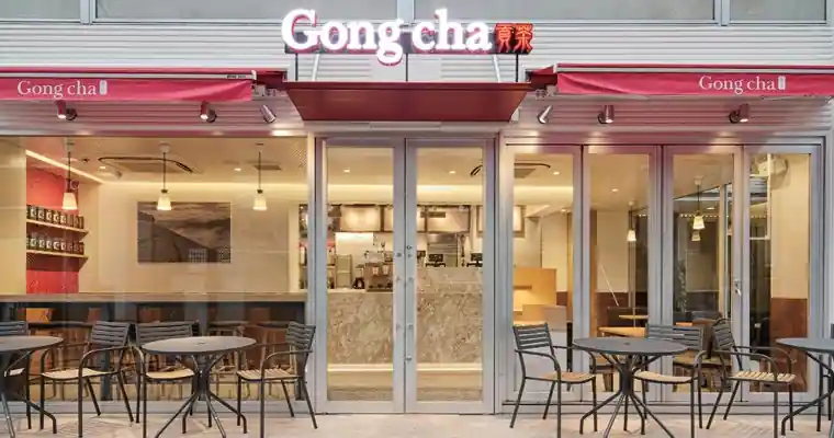 Gong Cha storefront with red awnings and outdoor tables and chairs