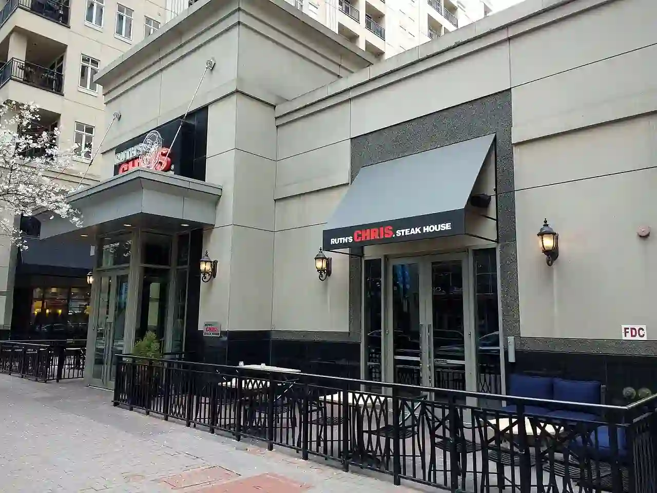 Photo of Ruth’s Chris Steak House entrance with visible signage, outdoor seating, and contemporary exterior design including wall lanterns and large windows.