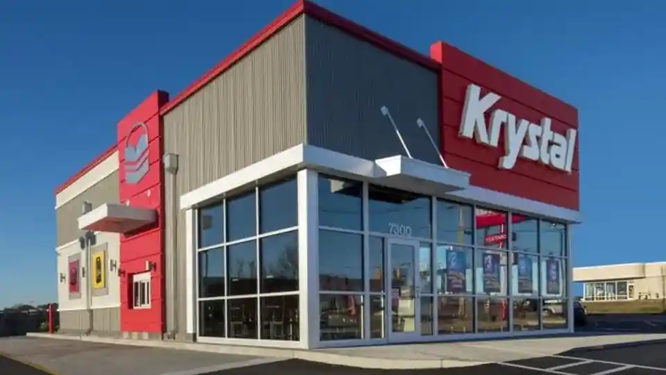 Krystal restaurant exterior featuring large glass windows, a bold red and gray color scheme, and prominent logo signage on a modern facade under a clear sky.