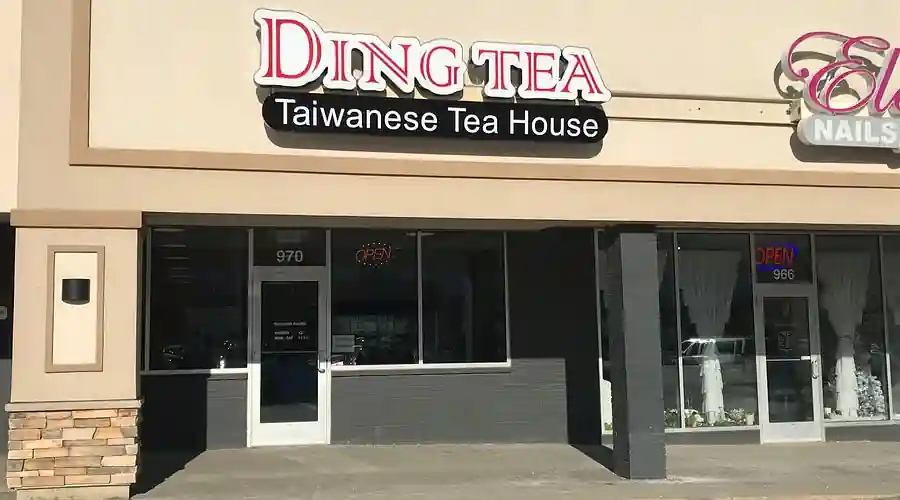 Storefront of Ding Tea Taiwanese Tea House with bold red and white signage, glass door numbered 970, and a neon “OPEN” sign; adjacent to a nail salon at number 966.