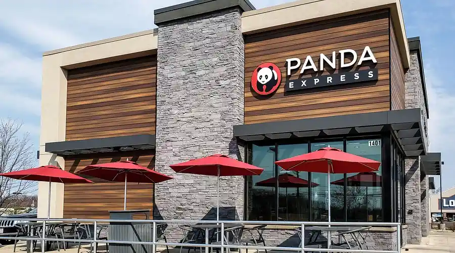 Panda Express restaurant exterior with wood and stone facade, red circular panda logo and text signage, outdoor seating shaded by red umbrellas, and address number “1401” visible on building.